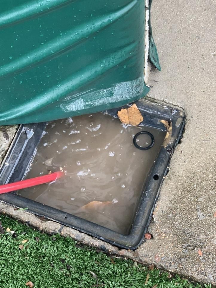 A Green Water Tank Is Sitting on The Ground Next to A Drain — Top To Bottom Plumbing in Garbutt, QLD