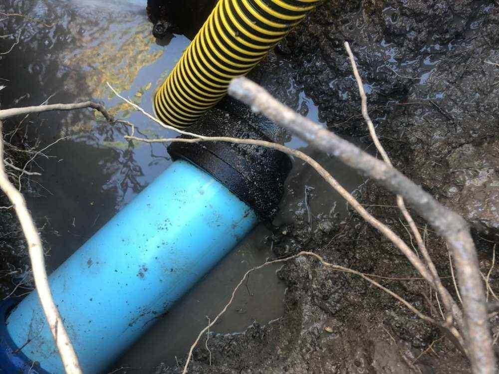 A Blue Pipe Is Laying in The Mud Next to A Yellow Hose — Top To Bottom Plumbing in Garbutt, QLD