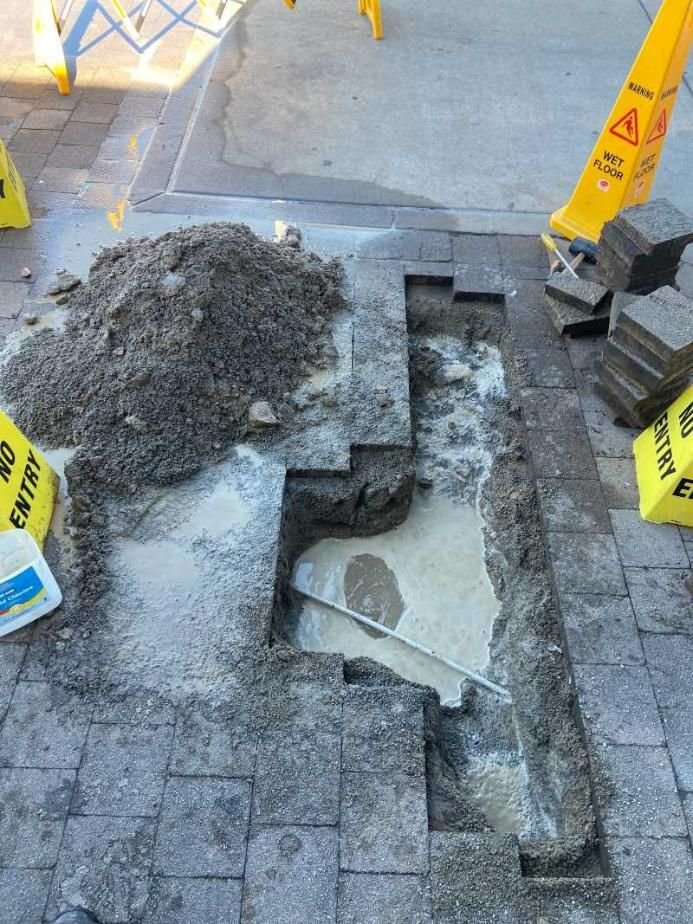 A Hole in The Ground with A Yellow Caution Sign in The Background — Top To Bottom Plumbing in Garbutt, QLD