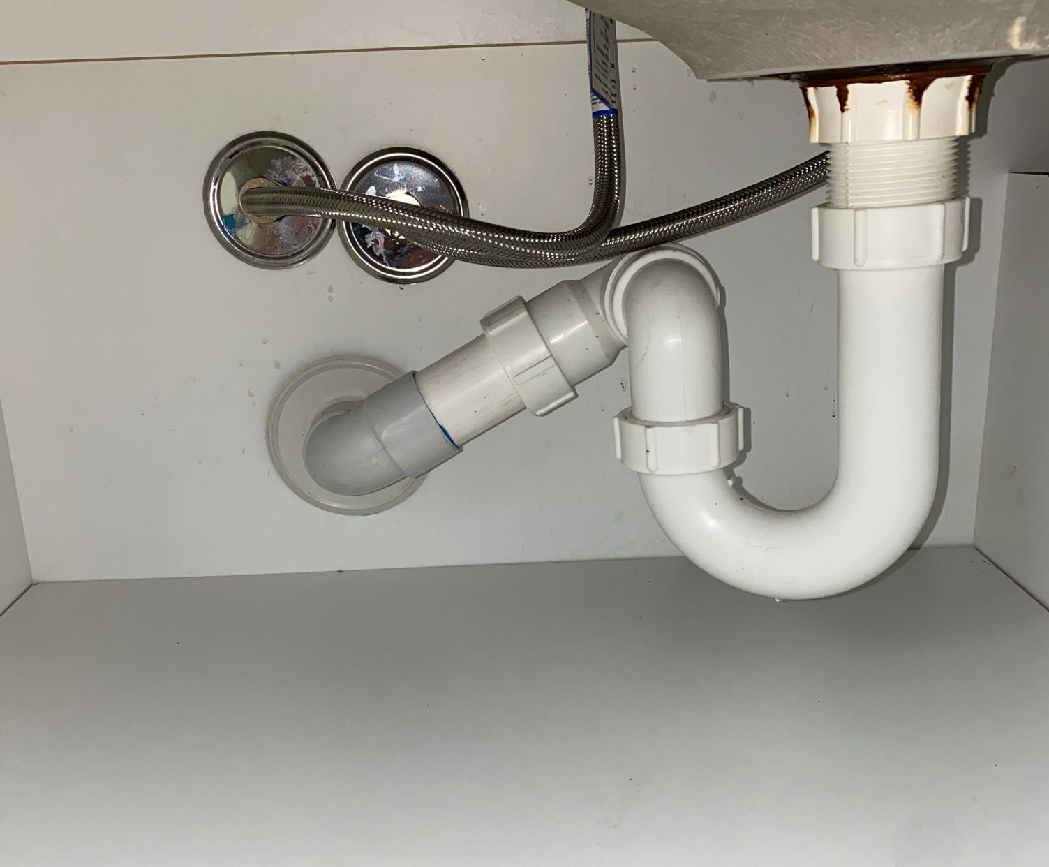 A Man Is Using a Machine to Drain a Drain Outside of A House — Top To Bottom Plumbing in Garbutt, QLD