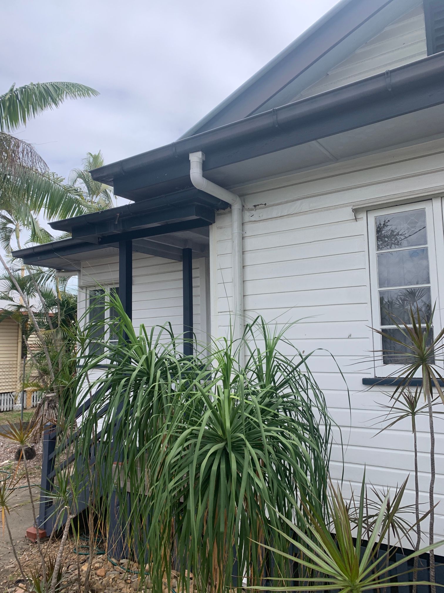 A Close up Of a White Corrugated Metal Roof with Trees in The Background — Top To Bottom Plumbing in Garbutt, QLD