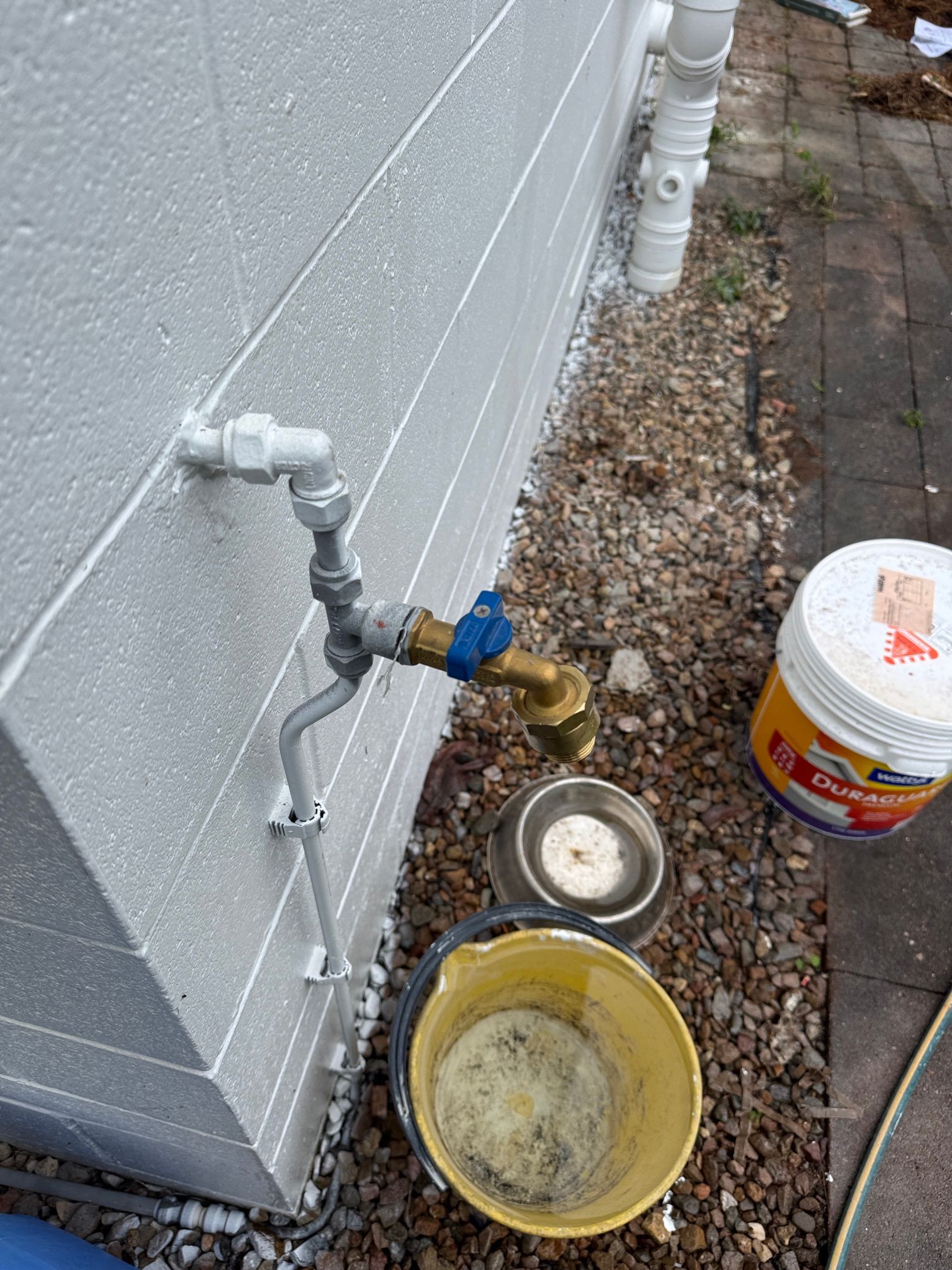 A Drain Pipe Is Being Installed in The Dirt in Front of A House — Top To Bottom Plumbing in Garbutt, QLD
