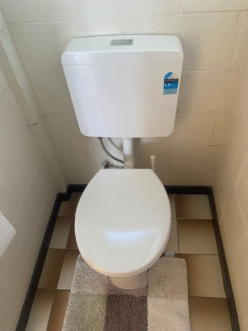 A White Toilet Is Sitting on A Tiled Floor in A Bathroom — Top To Bottom Plumbing in Garbutt, QLD