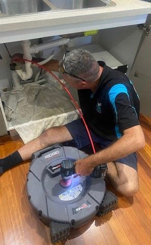 A Person Is Holding a Device in Front of A Sink — Top To Bottom Plumbing in Garbutt, QLD