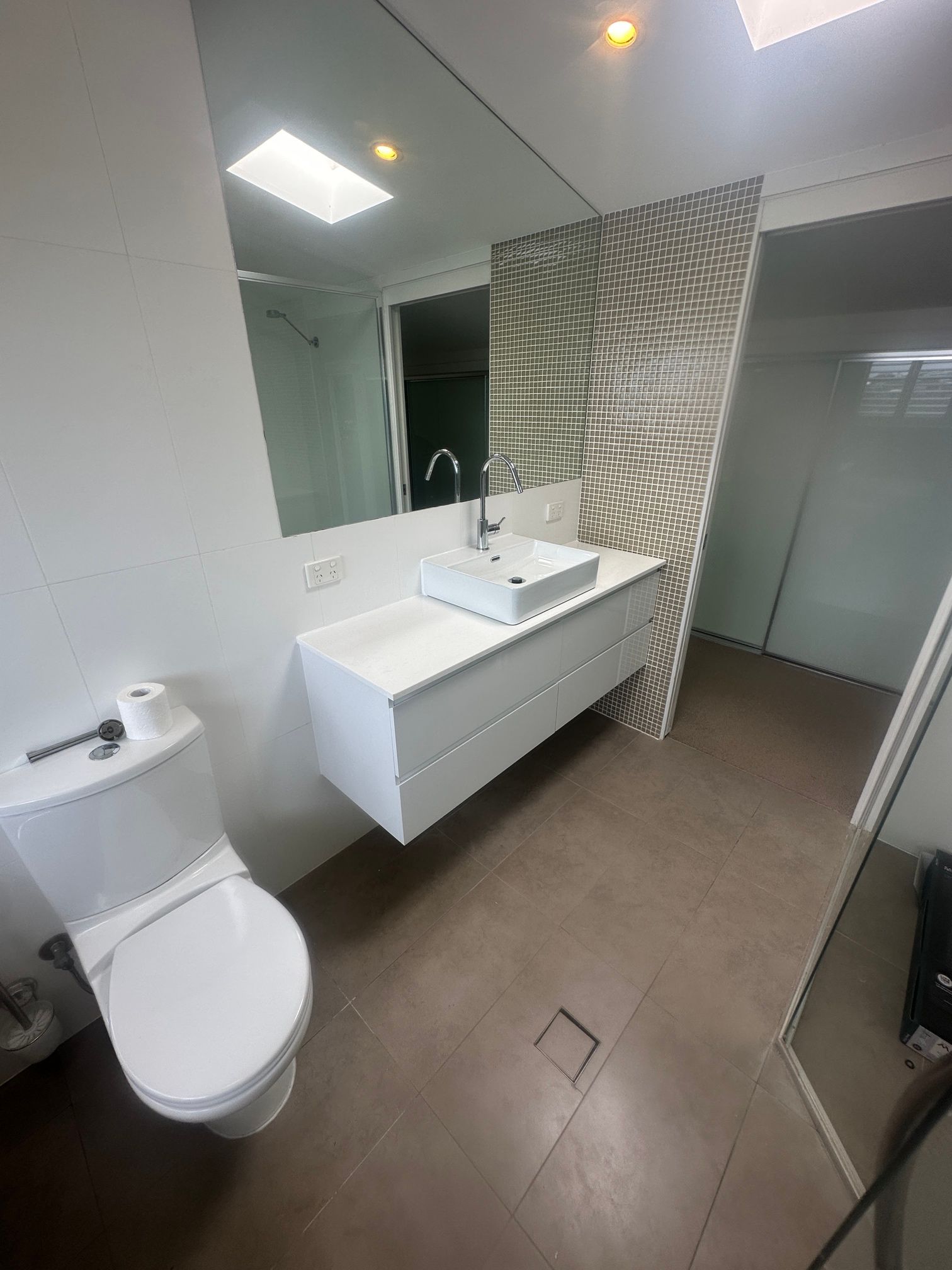 A Man Is Fixing a Toilet in A Bathroom — Top To Bottom Plumbing in Garbutt, QLD