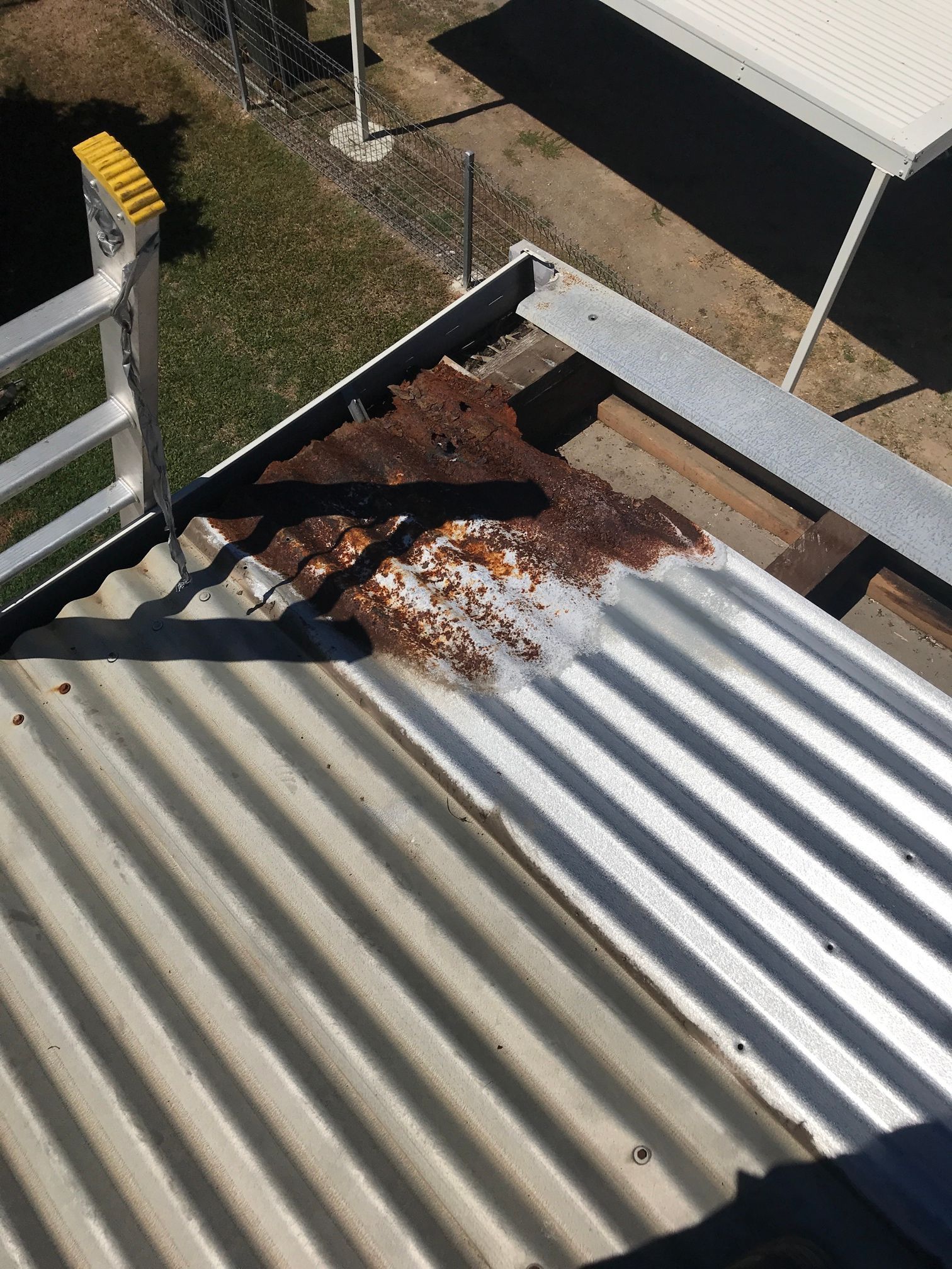 Rust damage on corrugated roofing sheet near roof edge.