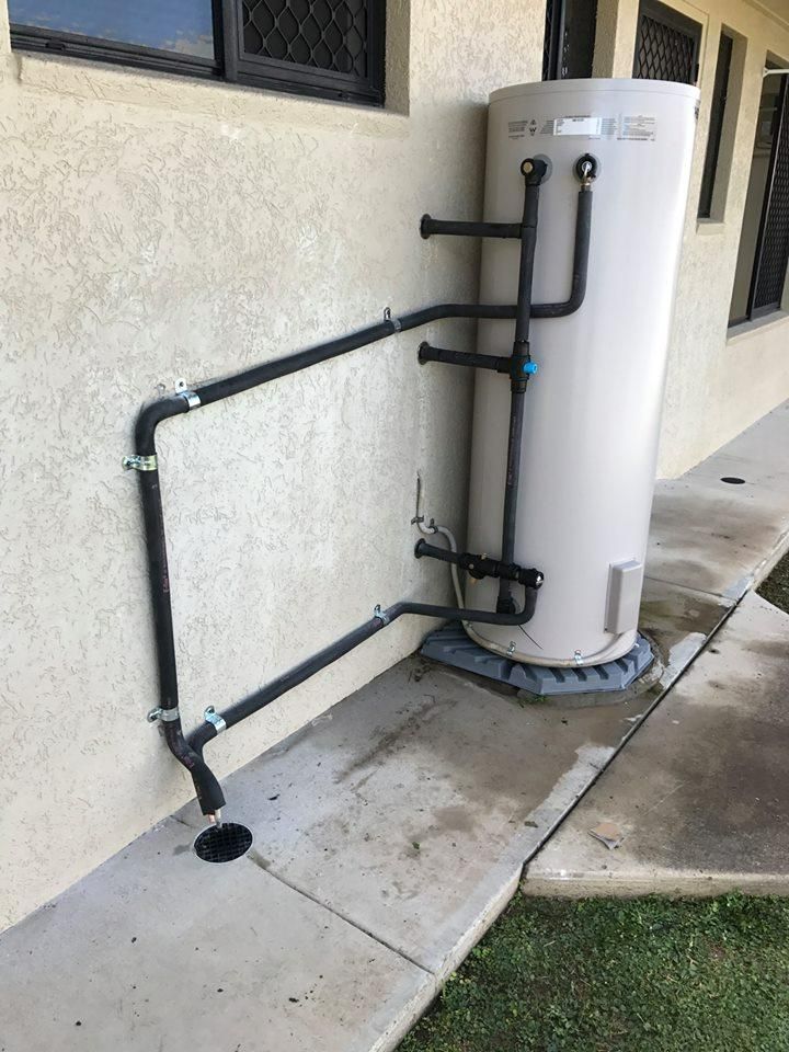 A Water Heater Is Sitting on The Sidewalk Next to A Building — Top To Bottom Plumbing in Garbutt, QLD