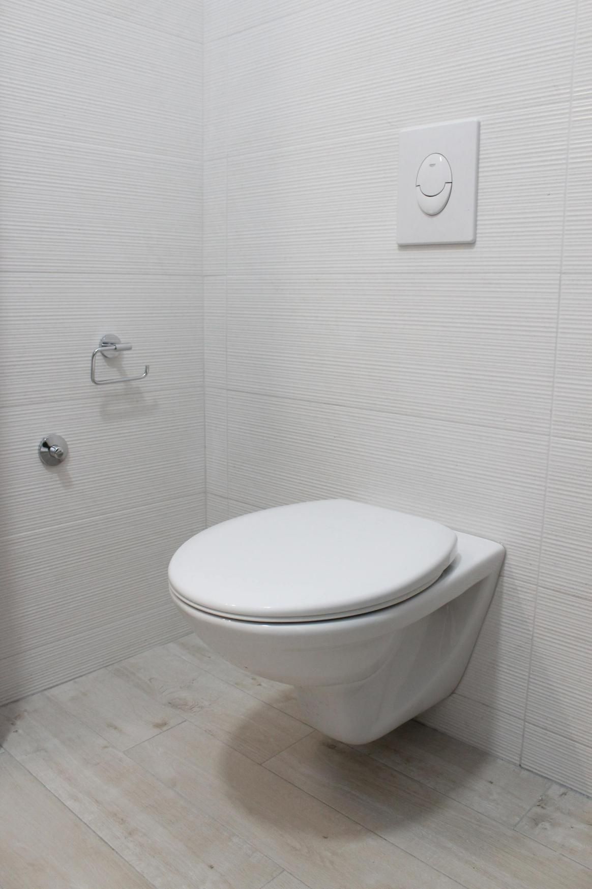 A White Toilet Is Mounted to The Wall in A Bathroom — Top To Bottom Plumbing in Garbutt, QLD