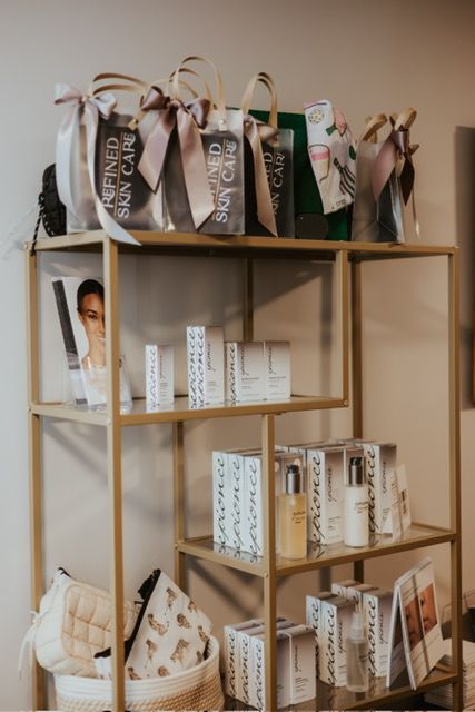 A gold display shelf holds skincare products, branded gift bags, and cosmetic pouches in a professional retail setting.