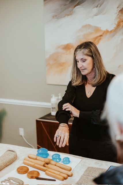 A person adjusts their sleeve at a table with therapy tools, including blue suction cups and wooden massage sticks.