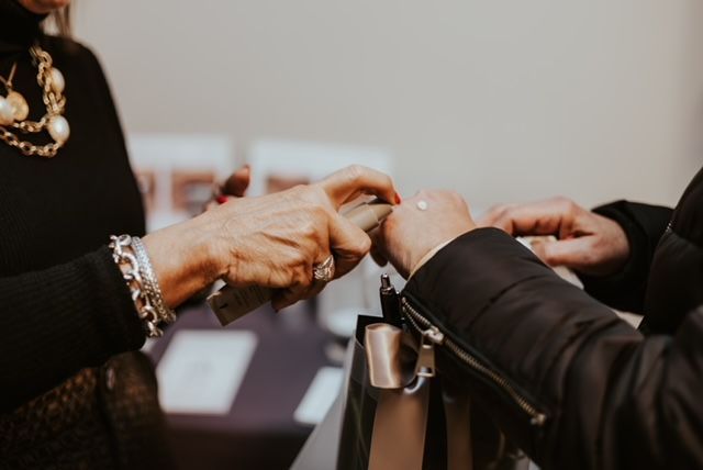 A person applies a small amount of product from a tube onto another person's hand.