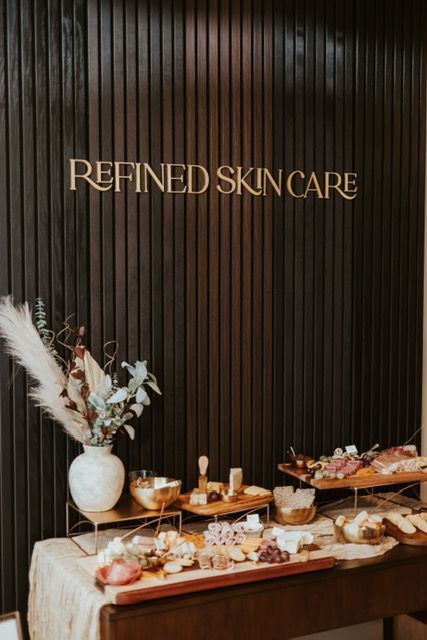 A charcuterie spread is set on a table beneath a wooden wall sign reading 