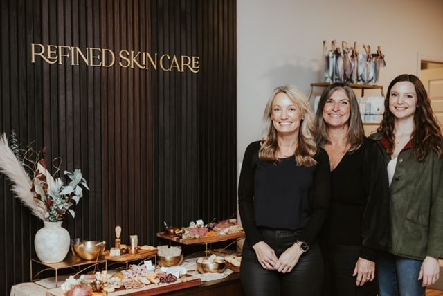 Three smiling people stand before a 