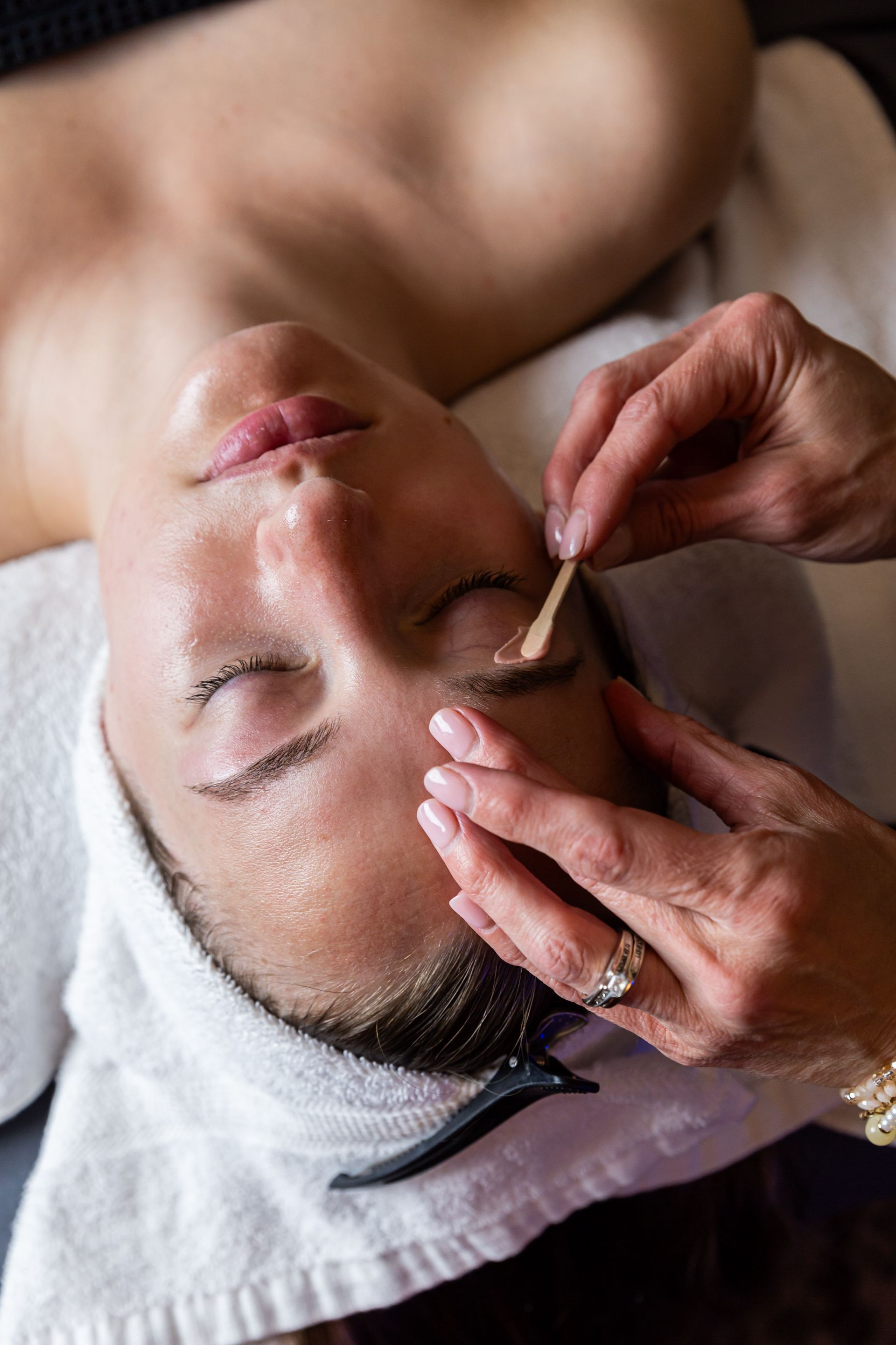 A woman is getting her eyebrows waxed at a spa.