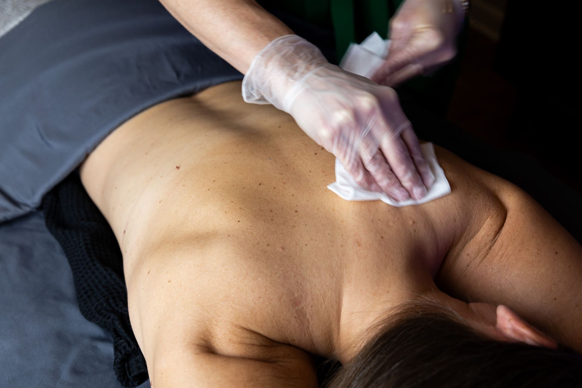 A woman is getting a massage and cleaning her back with a towel.