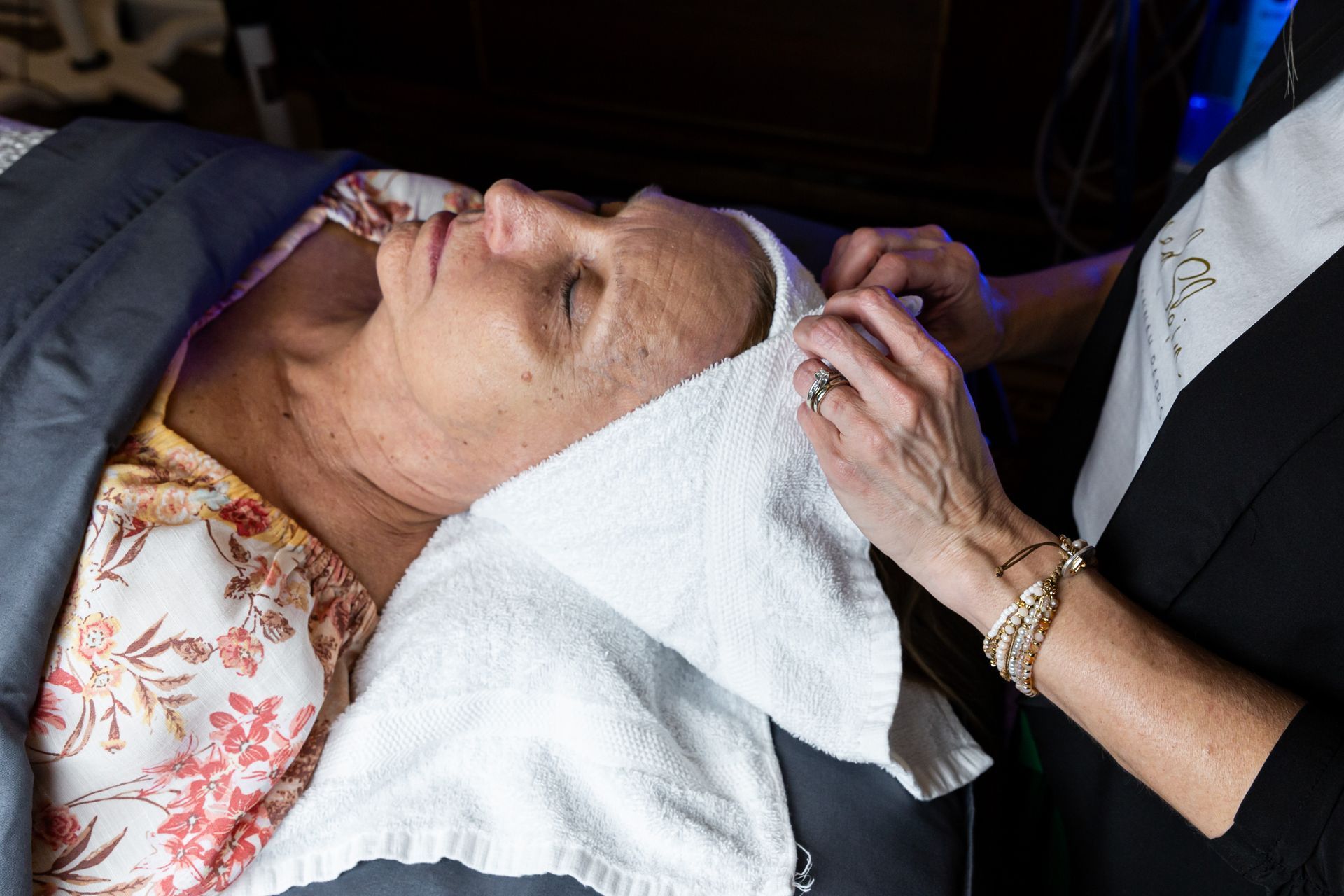 A woman is laying on a bed with a towel around her head.