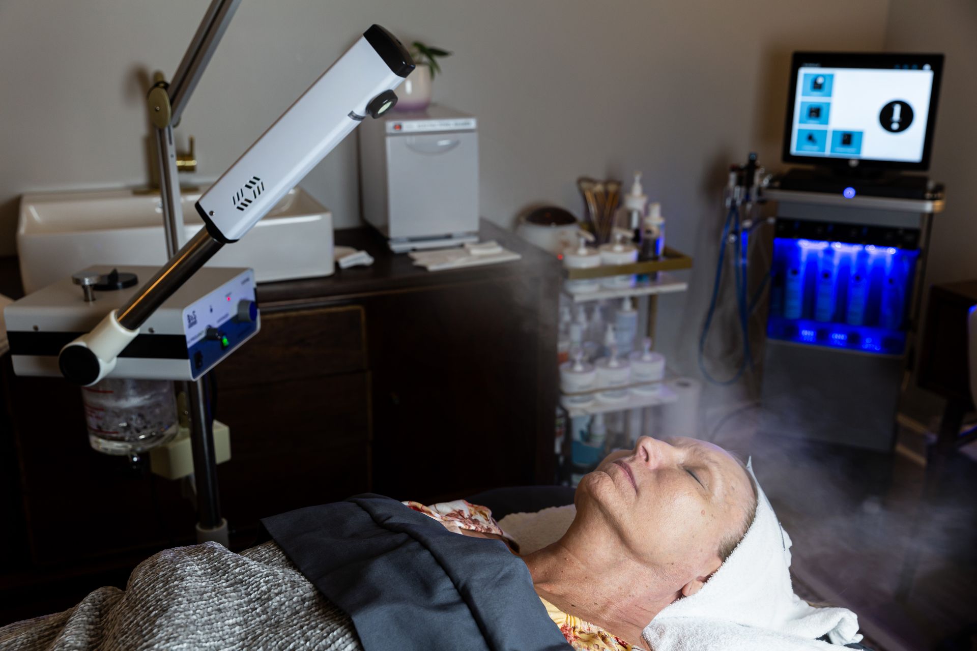 A woman is laying on a bed getting a facial treatment.