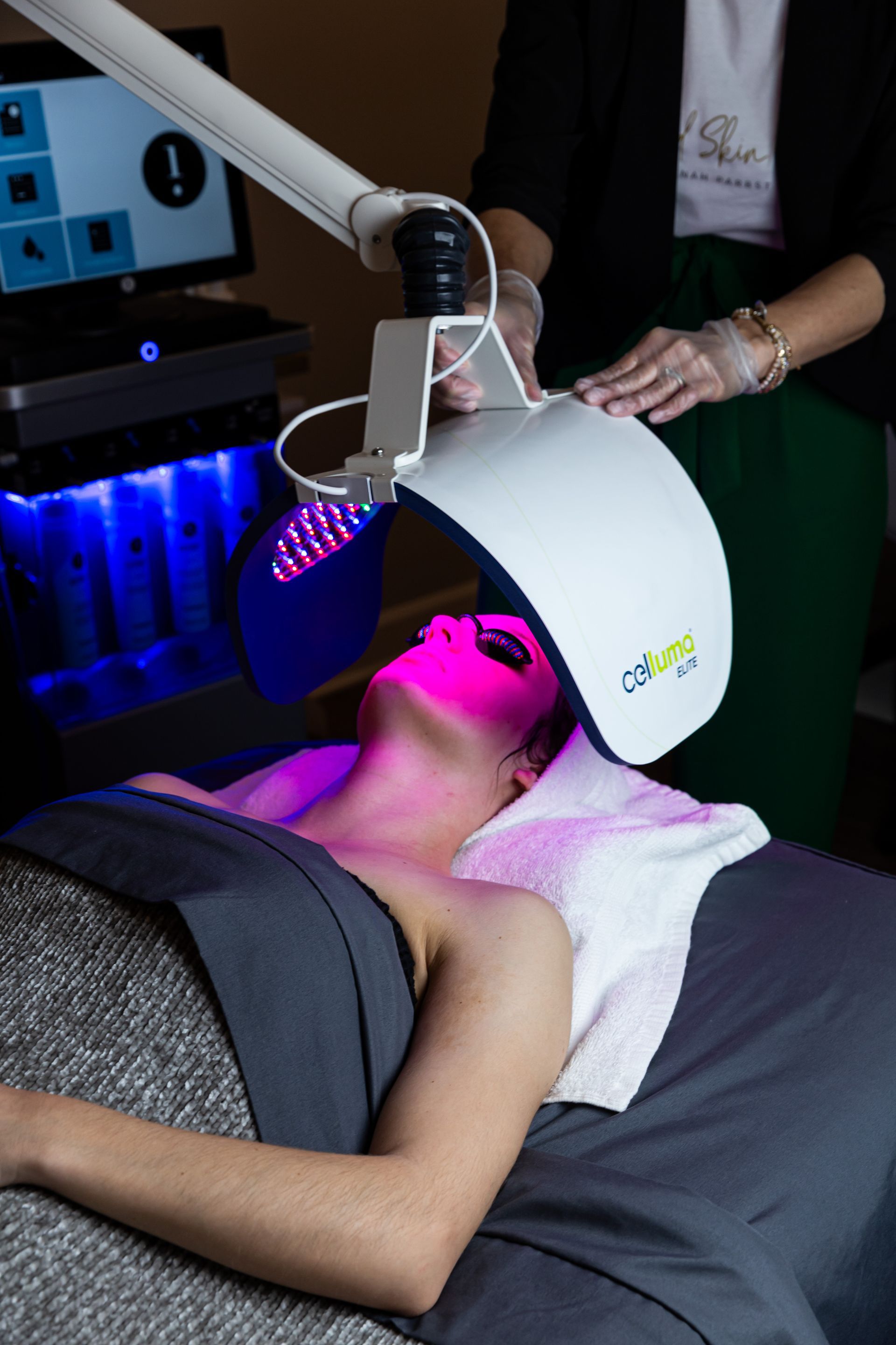 A woman is laying on a bed getting a treatment on her face