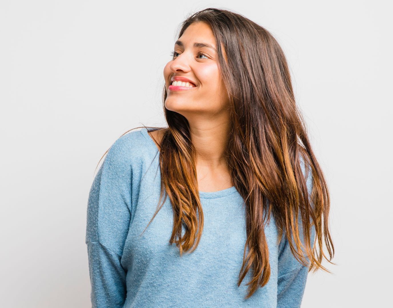 A woman in a blue sweater is smiling and looking up.