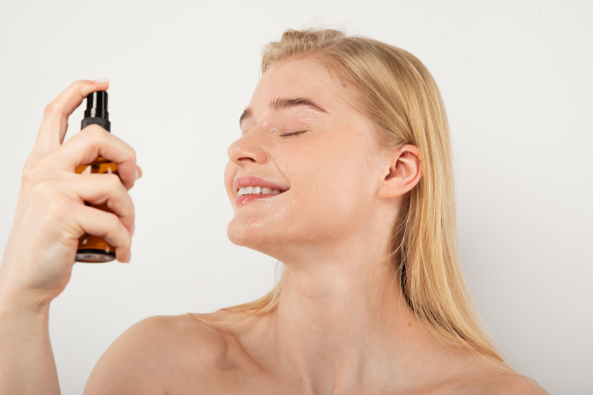 A woman is applying hydrating mist on her face