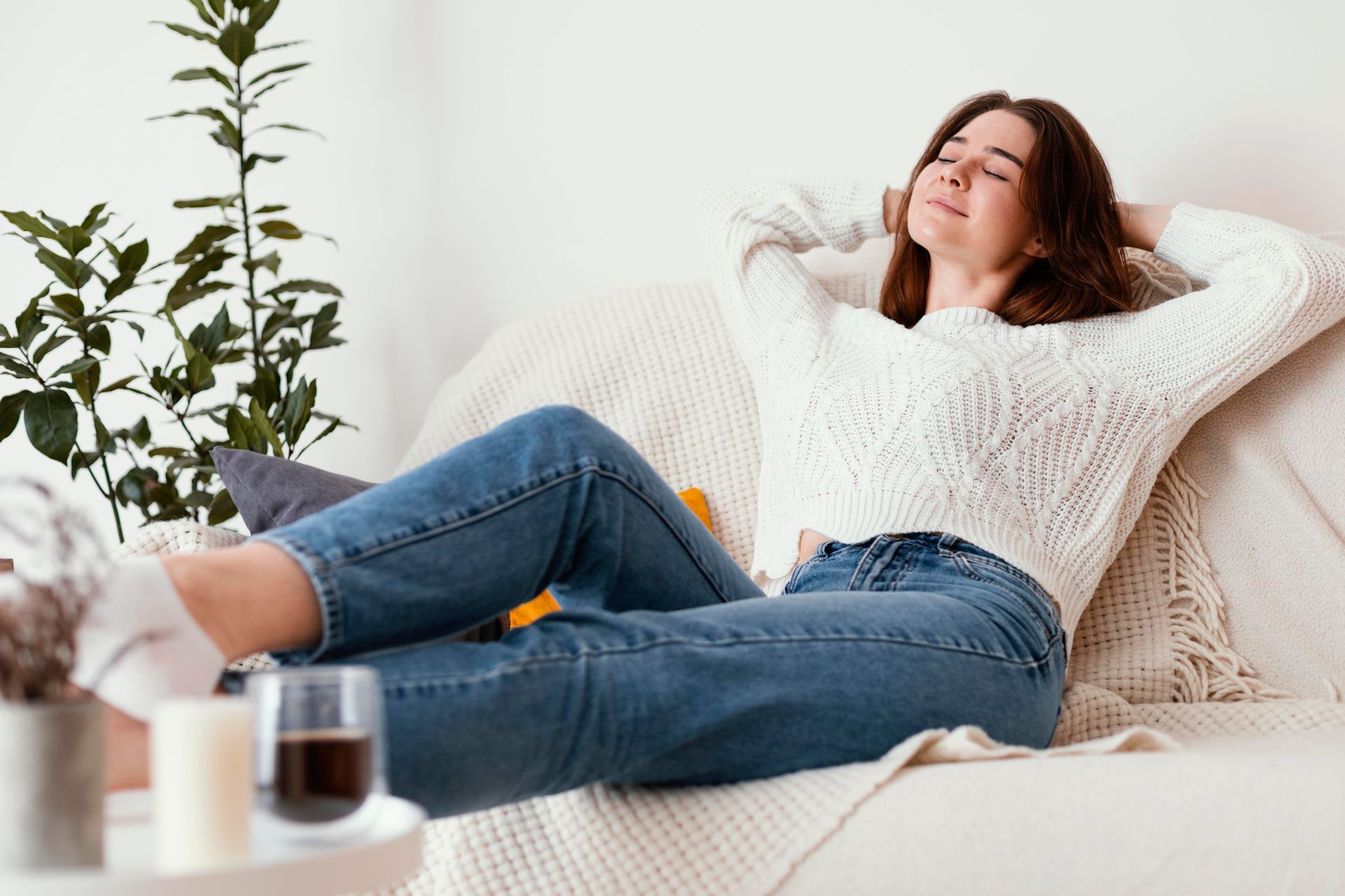 A woman is laying on a couch with her eyes closed.
