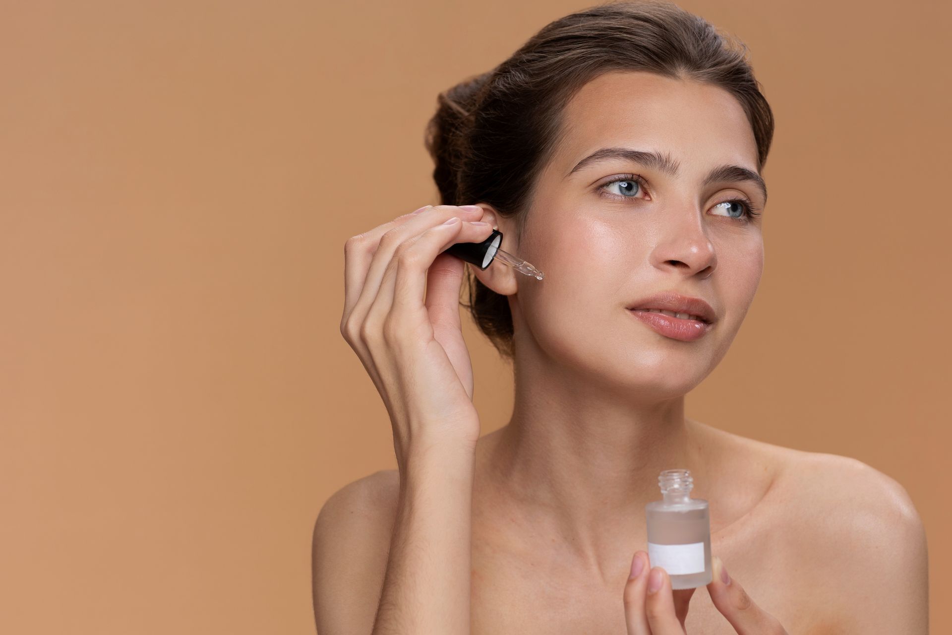 A woman is applying a serum to her face with a pipette.