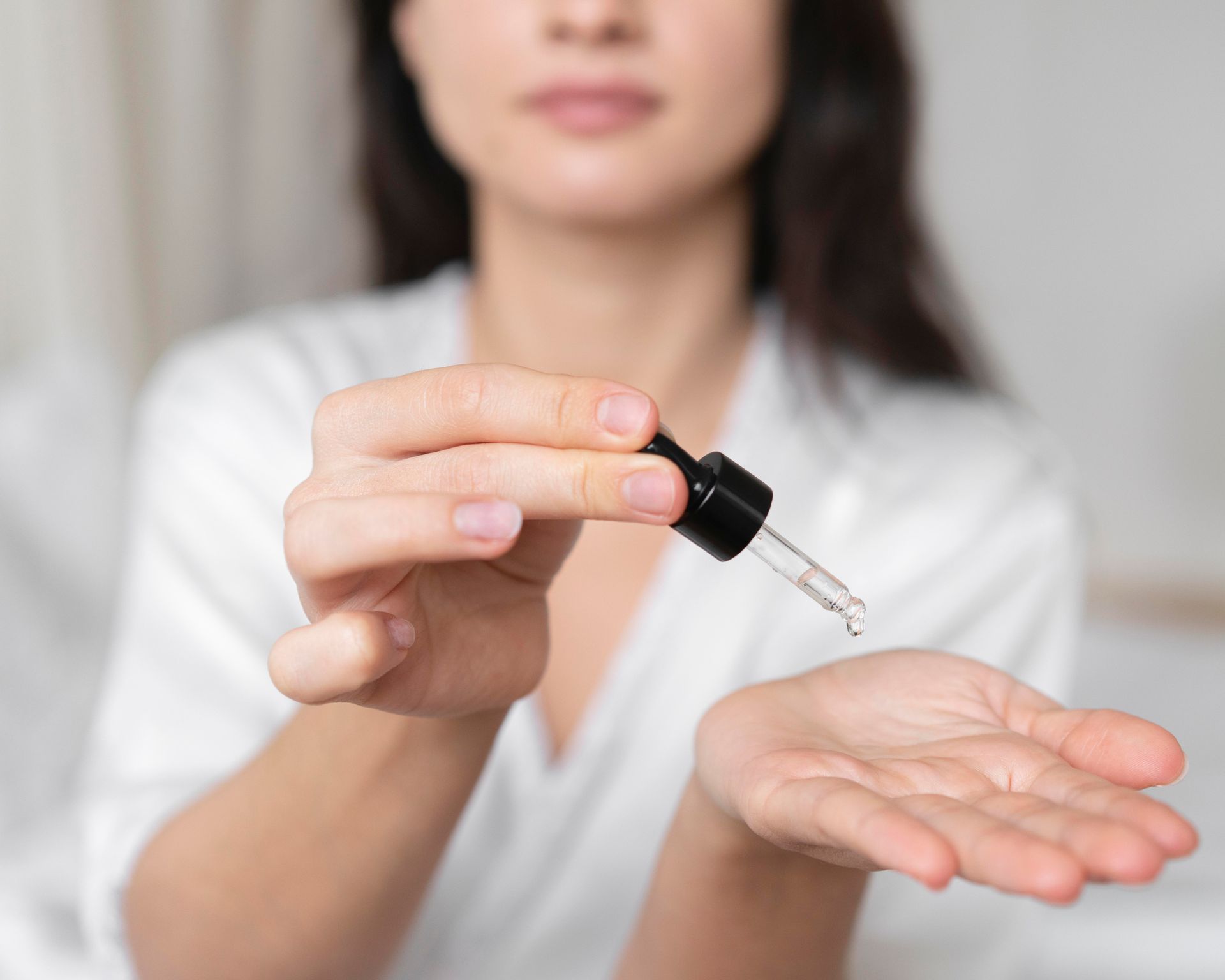 A woman is holding a dropper in her hand.