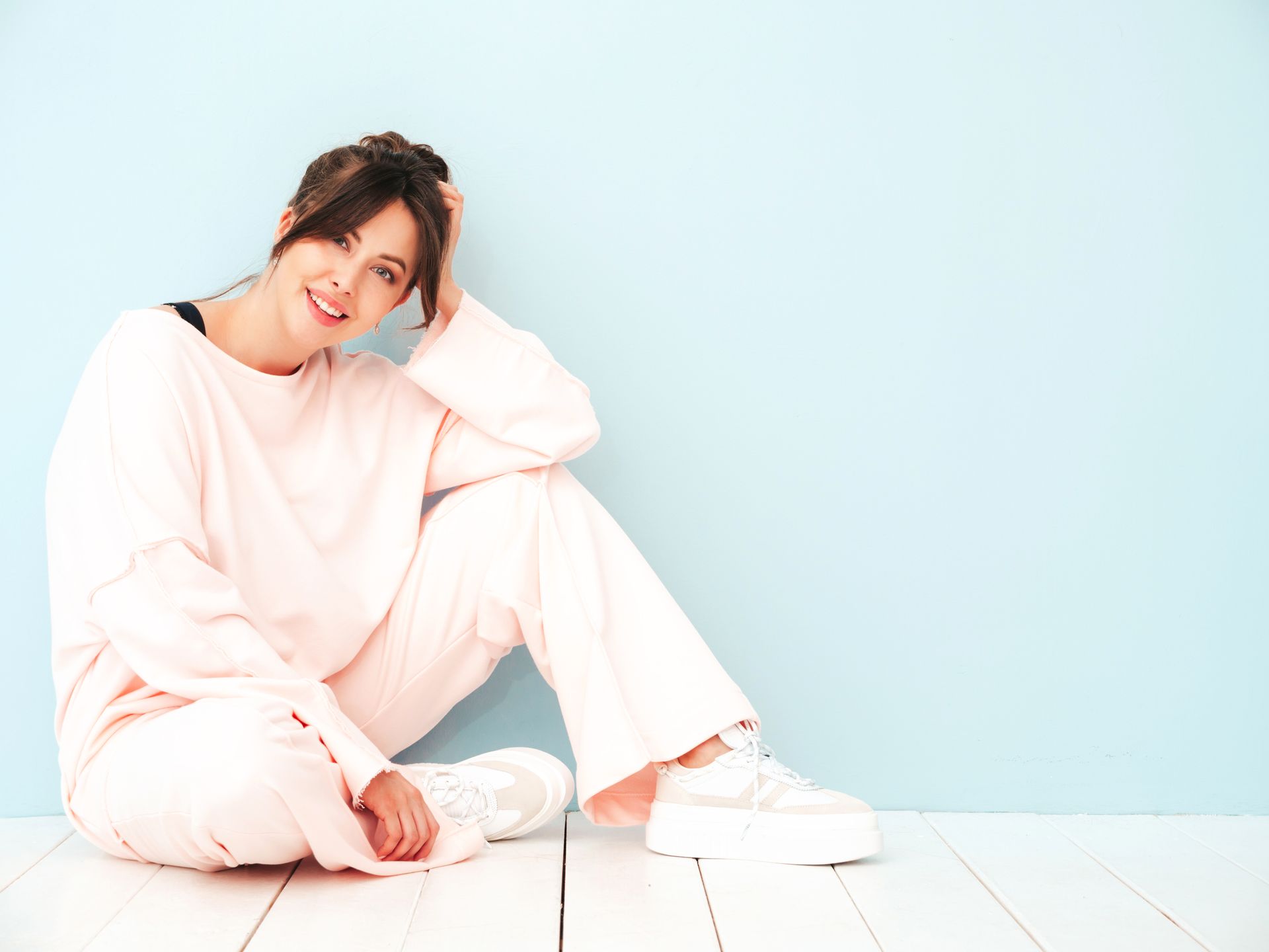 A woman is sitting on the floor in front of a blue wall.