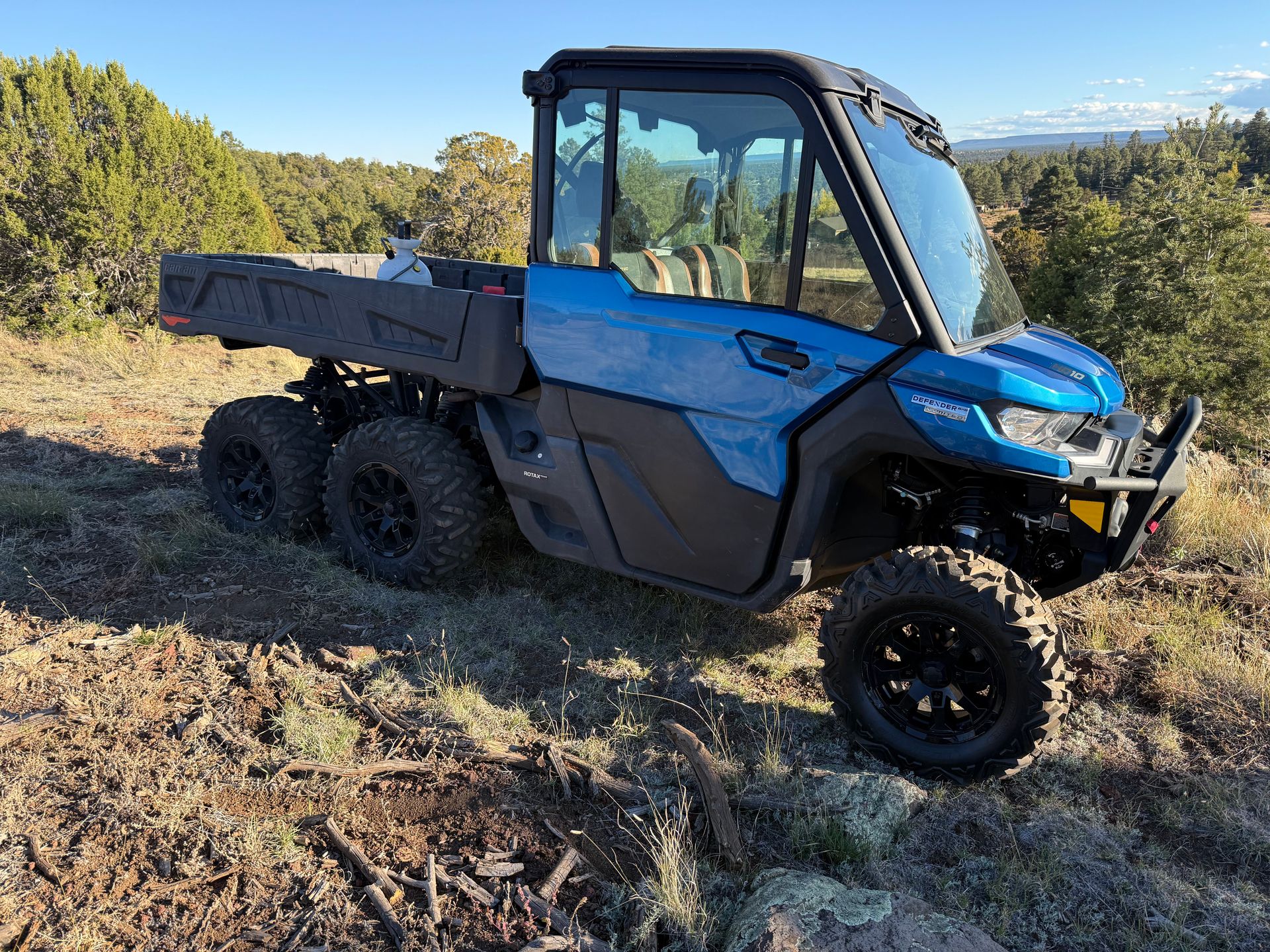 Dark blue Can-Am Defender side-by-side ATV with black roll cage, tires, and bed, parked on a surface.