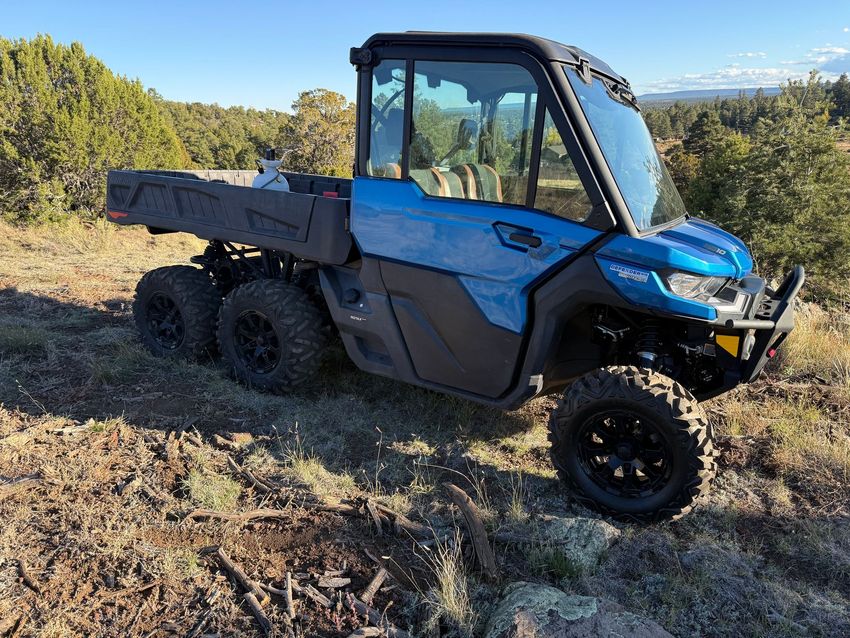 A blue utility terrain vehicle (UTV) is secured on a trailer in an outdoor setting.