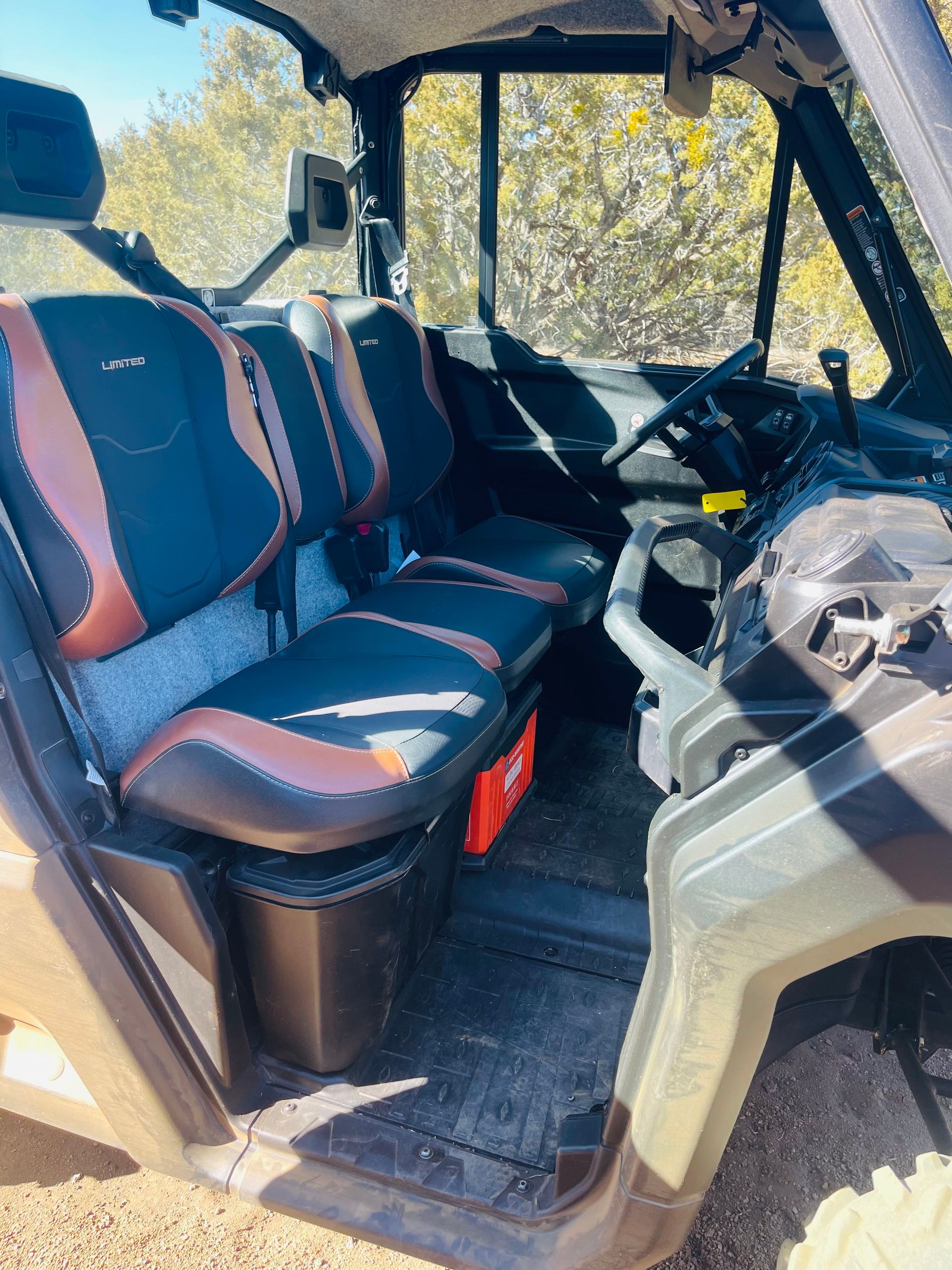 Interior view of a side-by-side vehicle with seats, dashboard, and a window; outdoors.