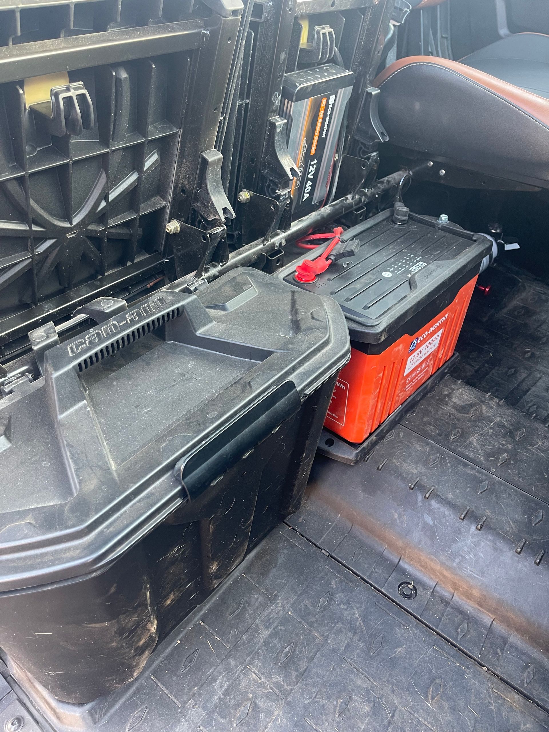 Black toolboxes and orange storage bin in a vehicle bed.