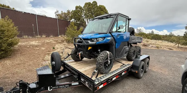 An ATV is secured to a trailer with straps.