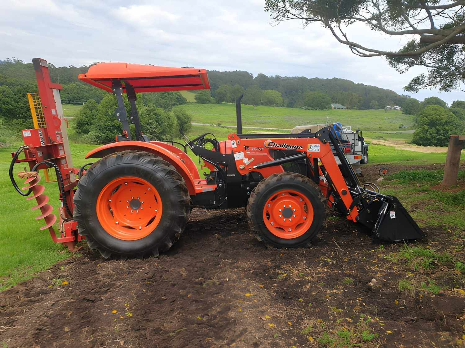 An Orange Tractor Working in A Muddy Field — Barry Brown Rural Contracting Service in Tinonee, NSW