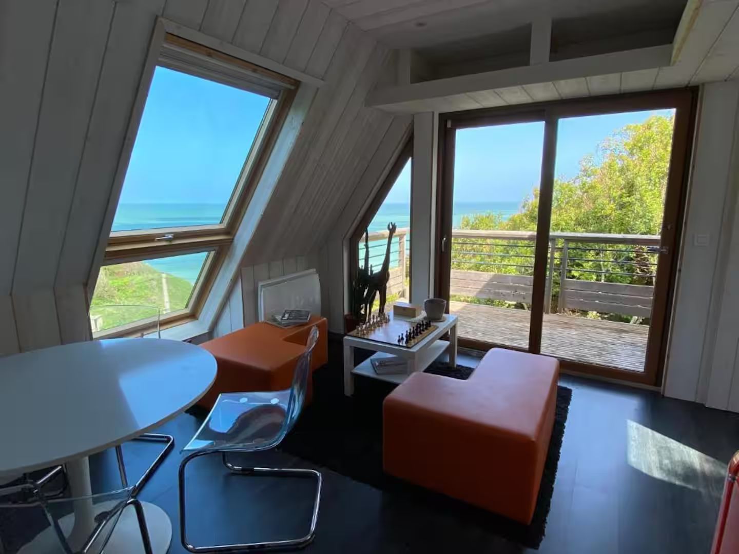 Un salon avec une table et des chaises et une vue sur l'océan