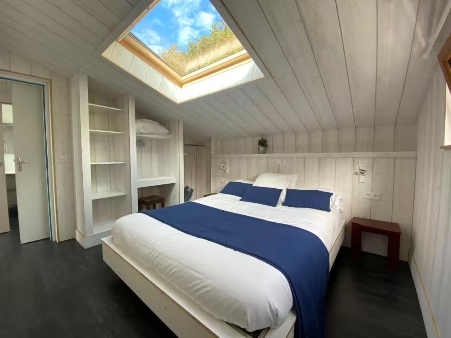 Une chambre avec un grand lit et une lucarne au plafond.