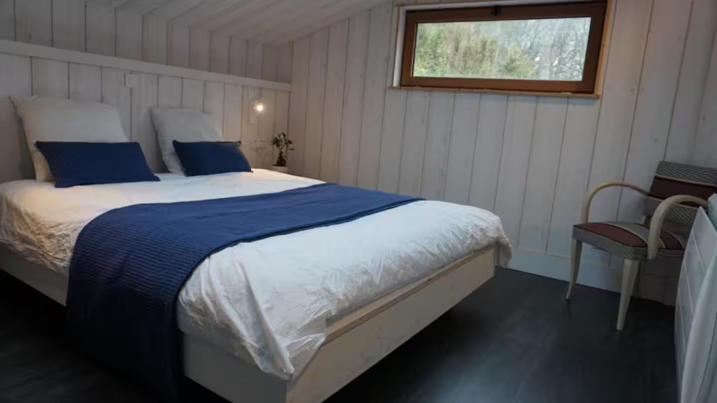 Une chambre avec un lit, une chaise et une fenêtre.