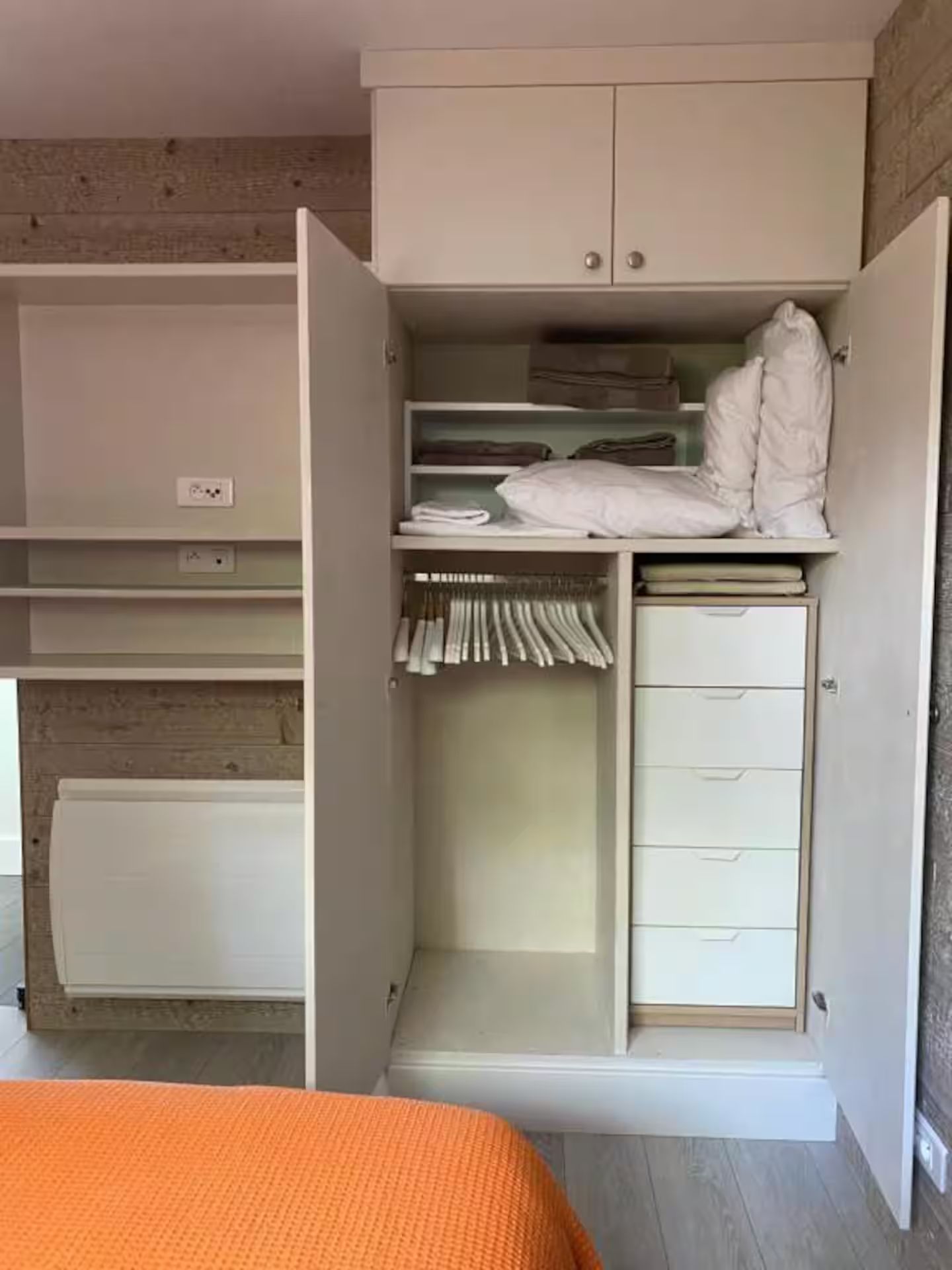Une chambre avec un lit et une armoire avec la porte ouverte.