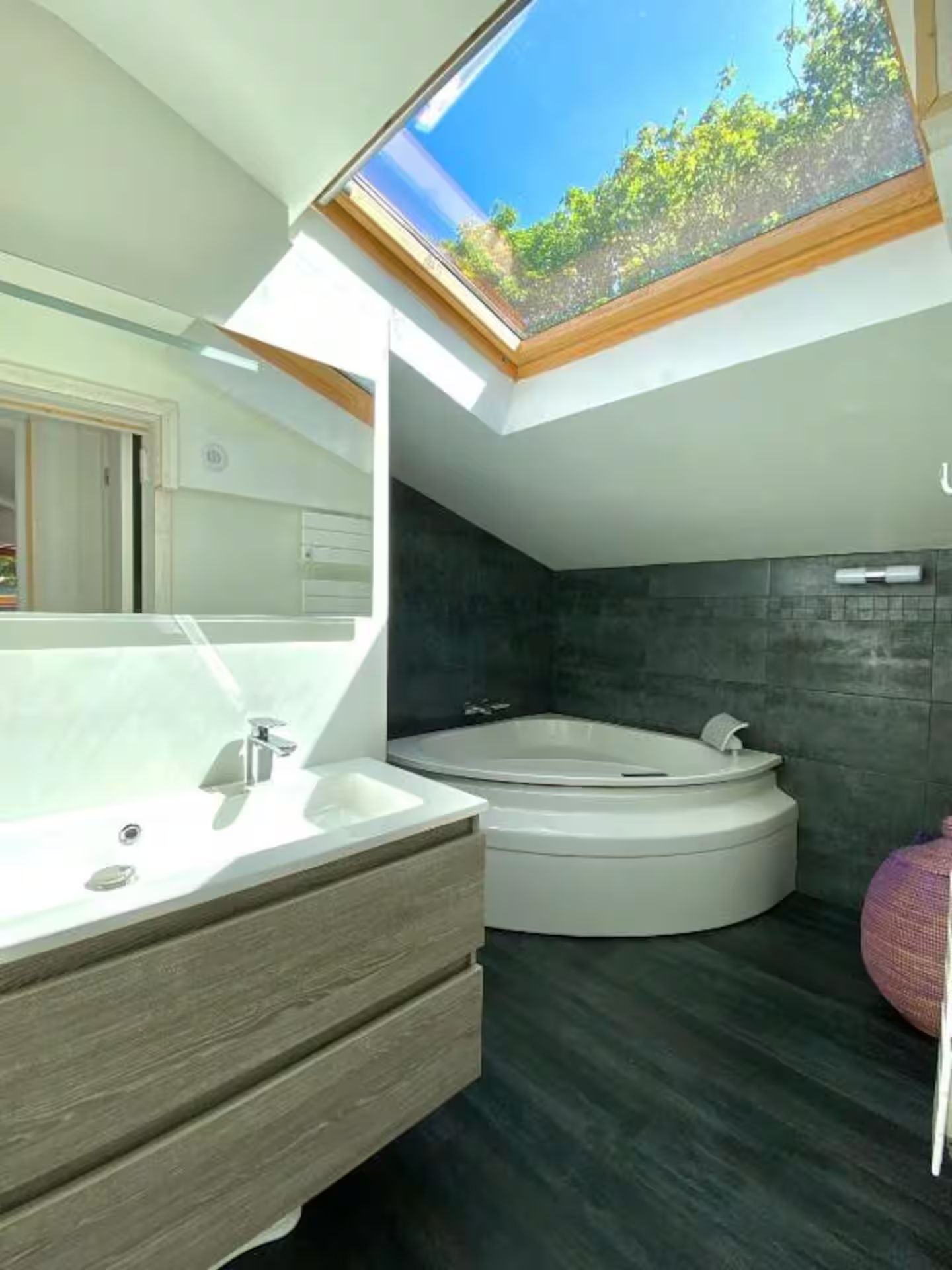 Une salle de bain avec baignoire, lavabo, miroir et puits de lumière