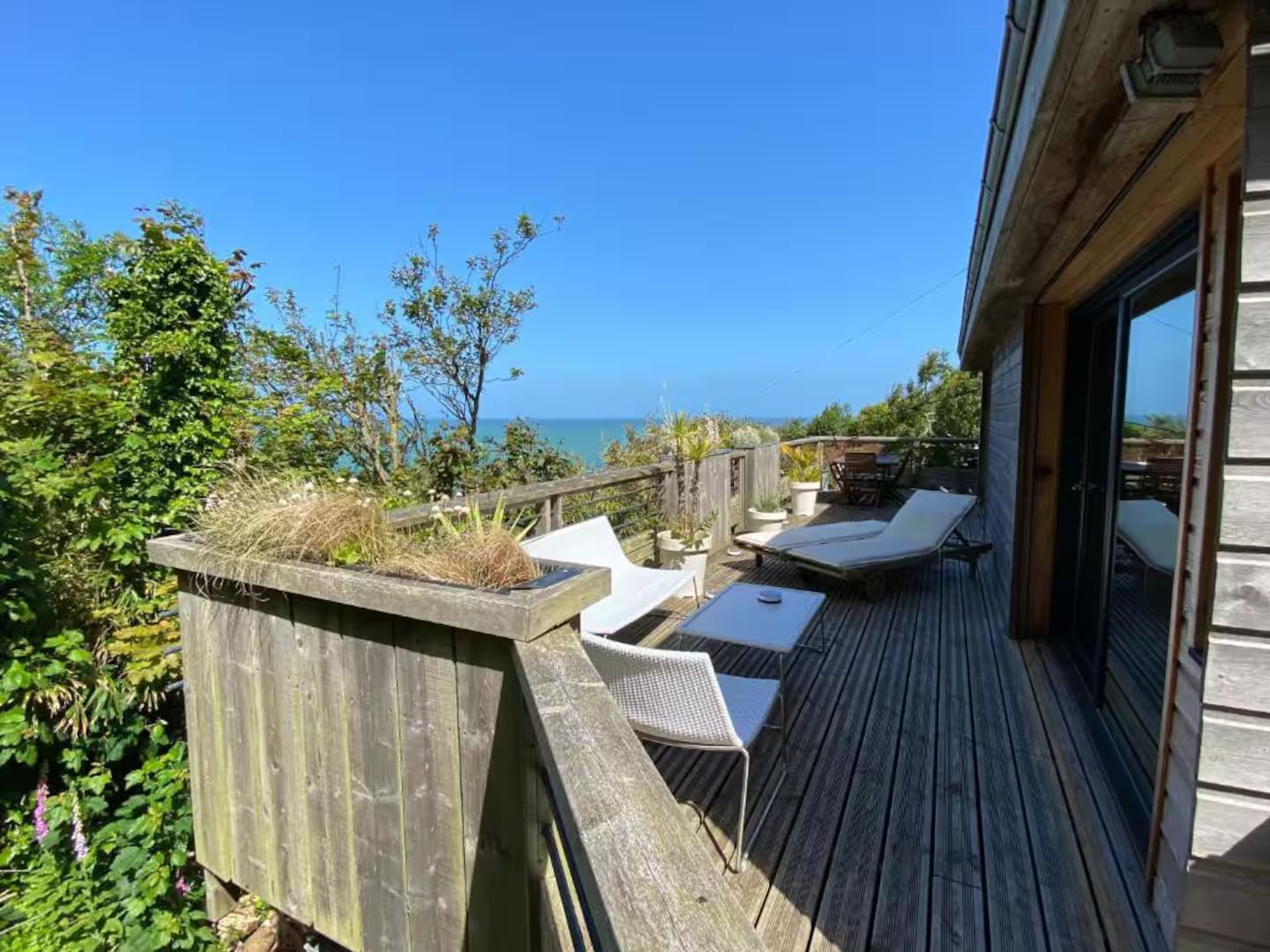 Une terrasse en bois avec des chaises et une table donnant sur l'océan.