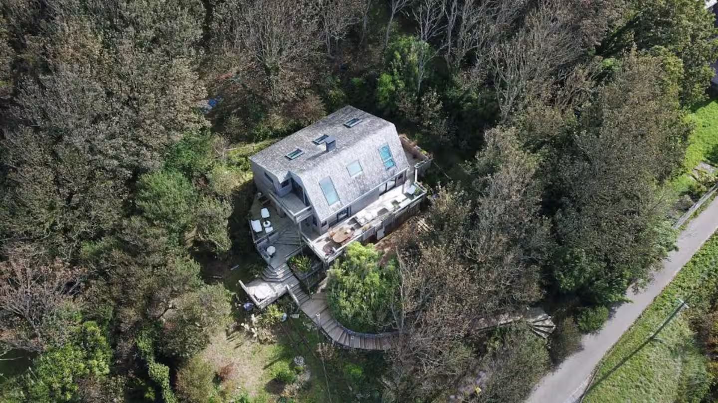 Une vue aérienne d'une maison entourée d'arbres et d'une route.