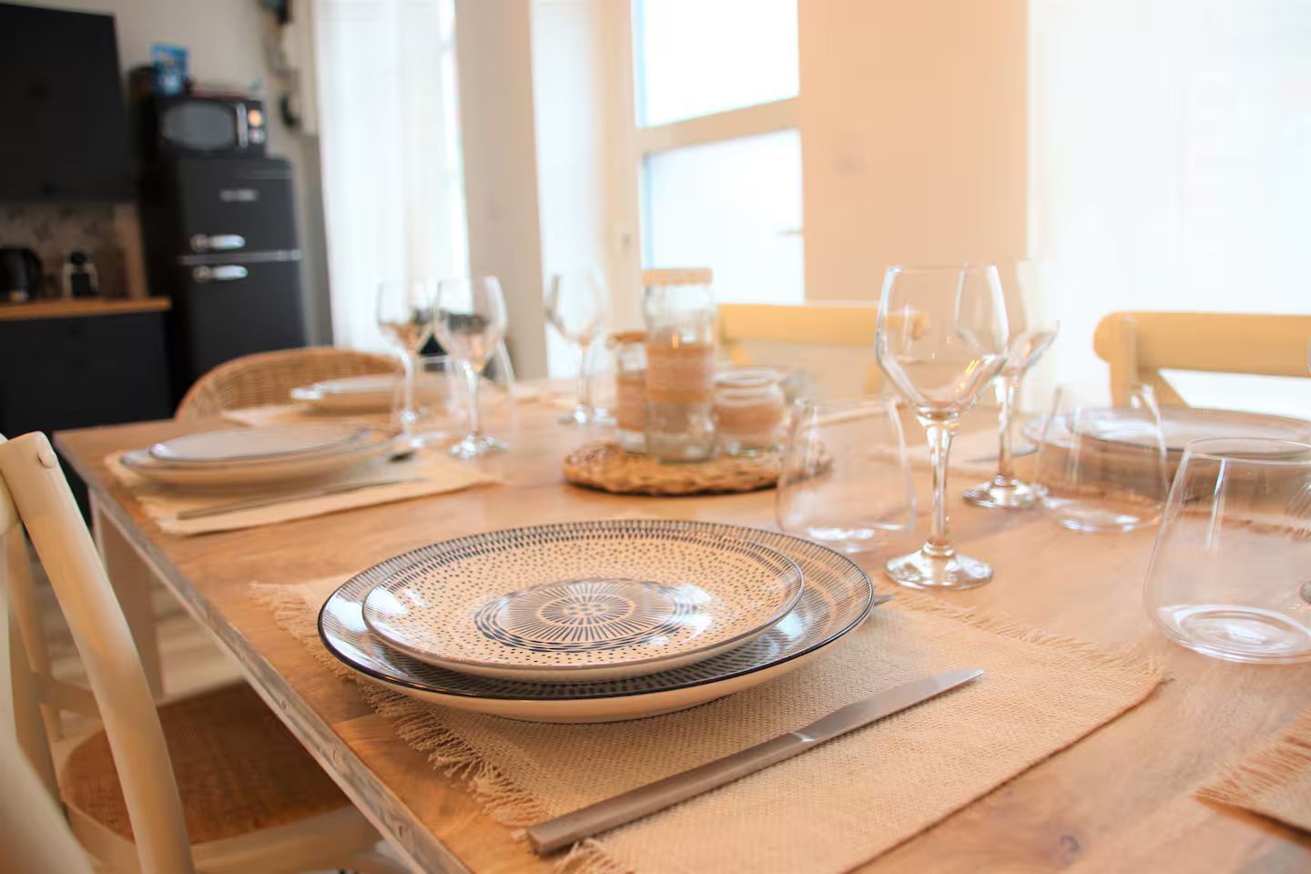 Une table à manger en bois avec des assiettes, des verres et des ustensiles dessus.
