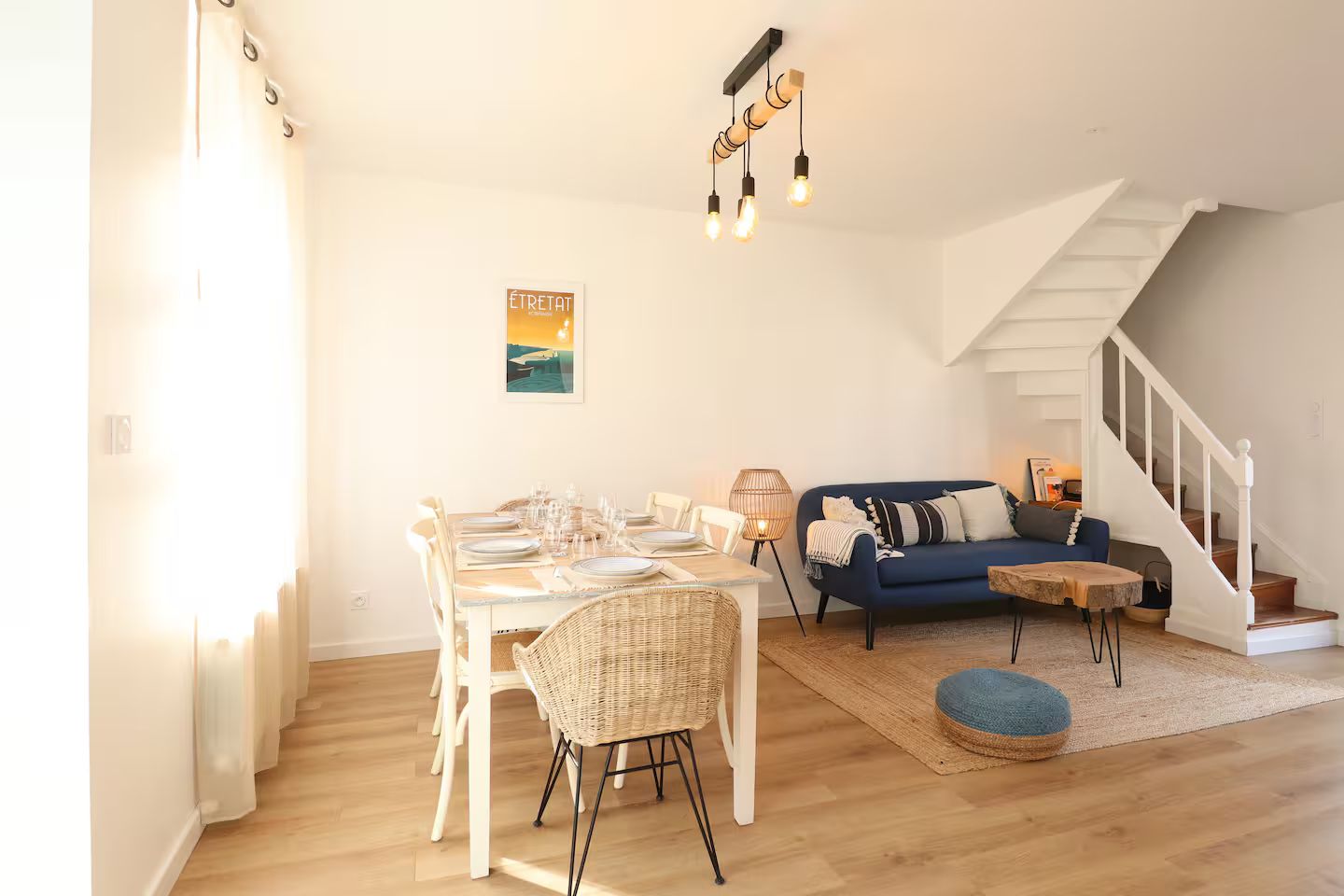 Un salon avec un canapé, une table et des chaises et des escaliers.