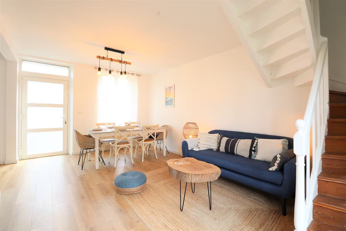 Un salon avec un canapé bleu, une table, des chaises et des escaliers.