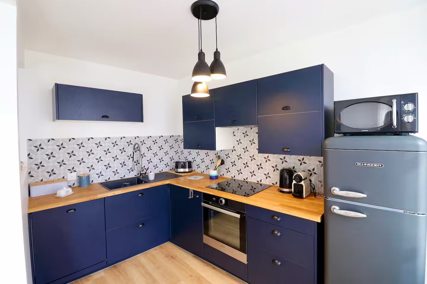 Une cuisine avec des armoires bleues, une cuisinière, un réfrigérateur et un micro-ondes.