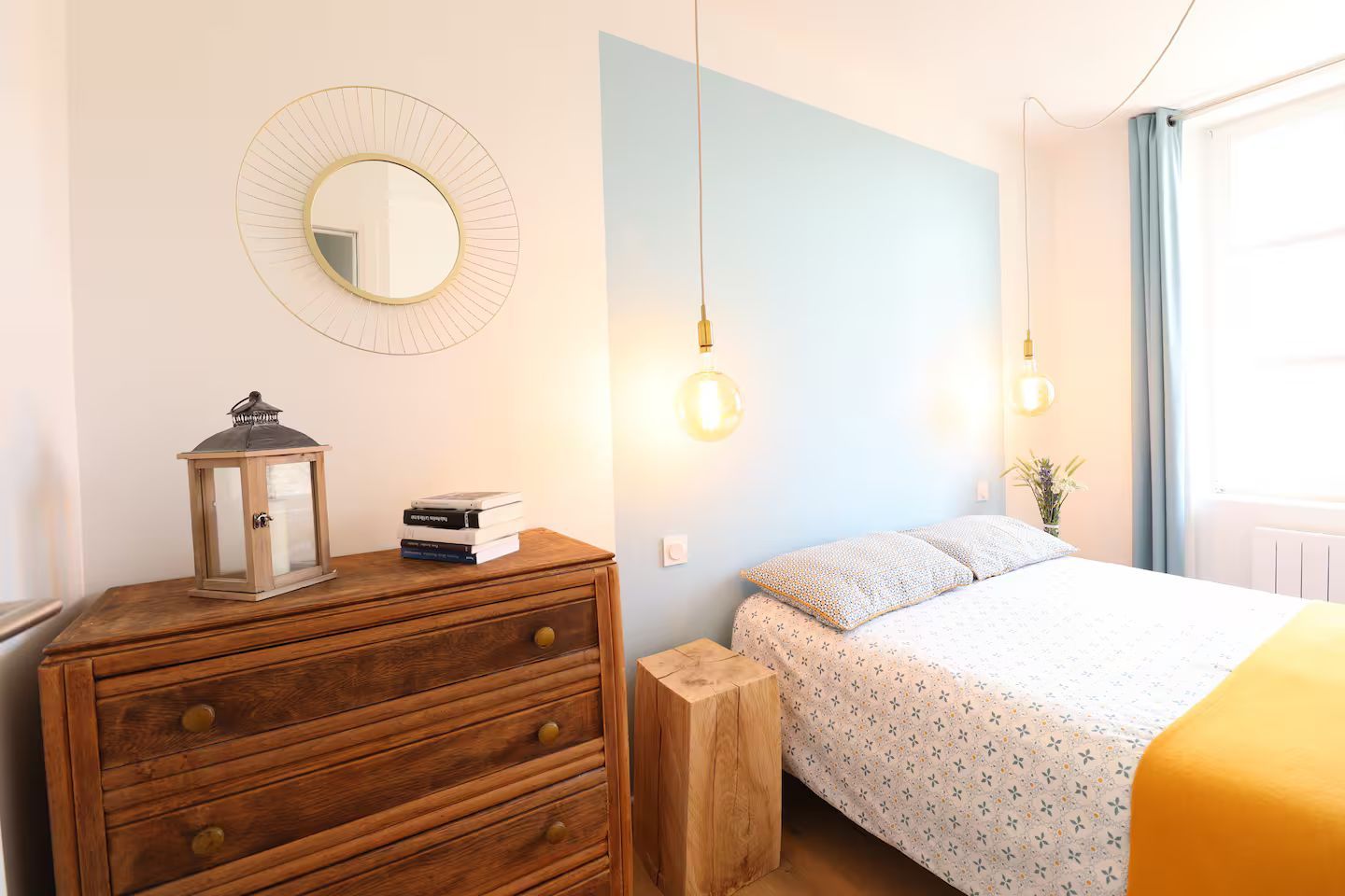 Une chambre avec un lit, une commode et un miroir.