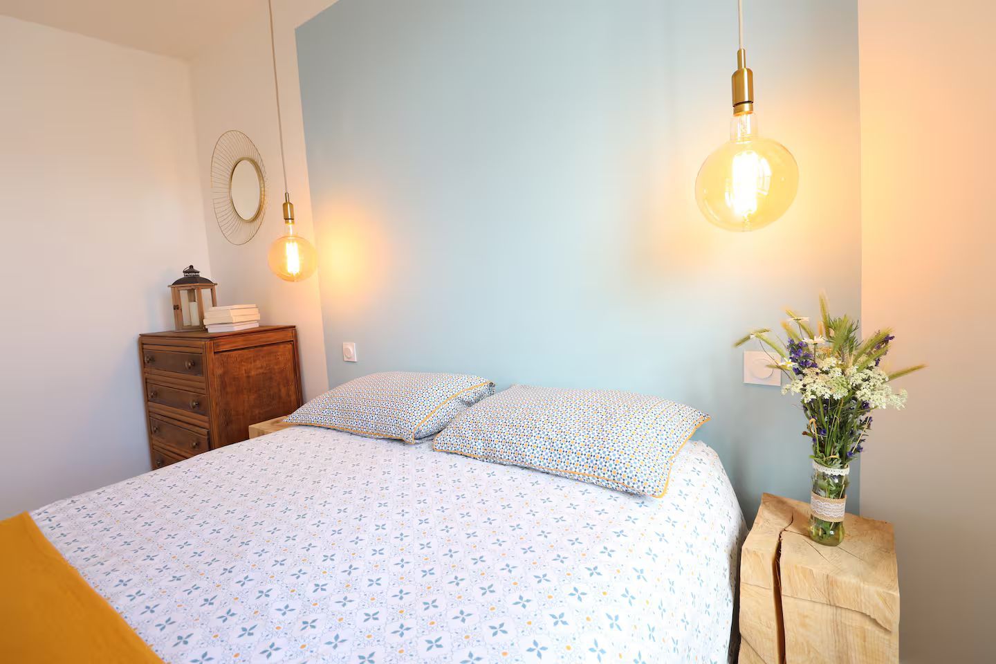 Une chambre avec un lit et un vase de fleurs sur une table de chevet.