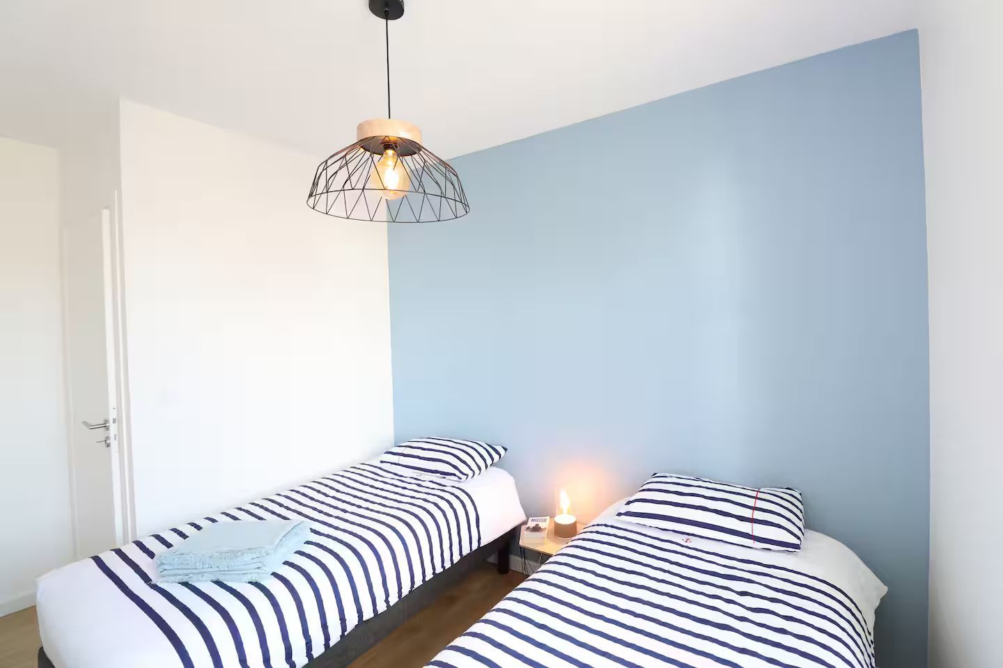 Une chambre avec deux lits et une lampe suspendue au plafond.