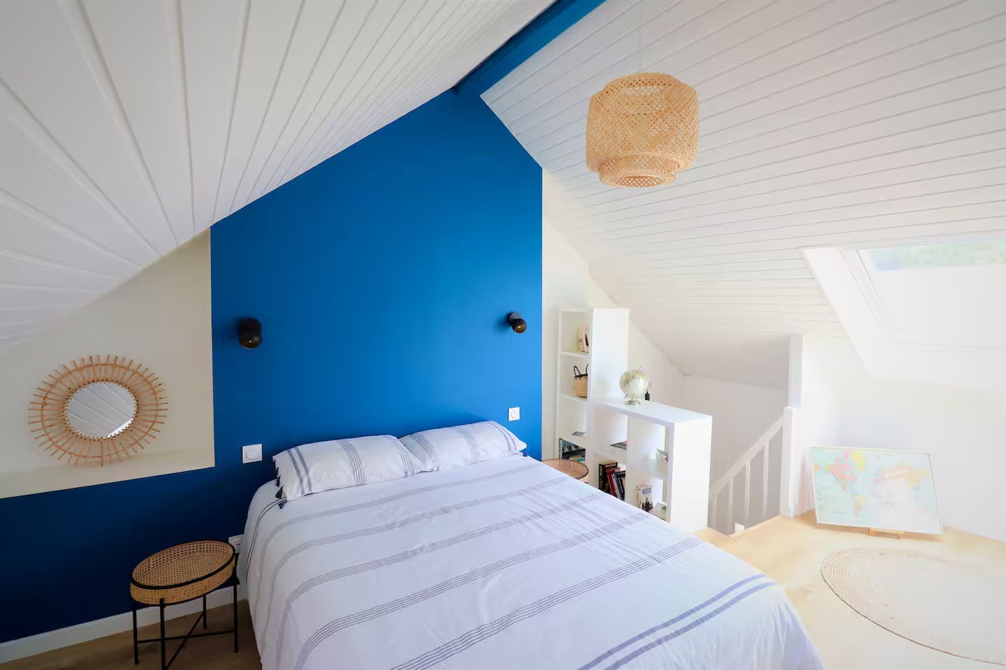 Une chambre avec un mur bleu et un lit blanc.