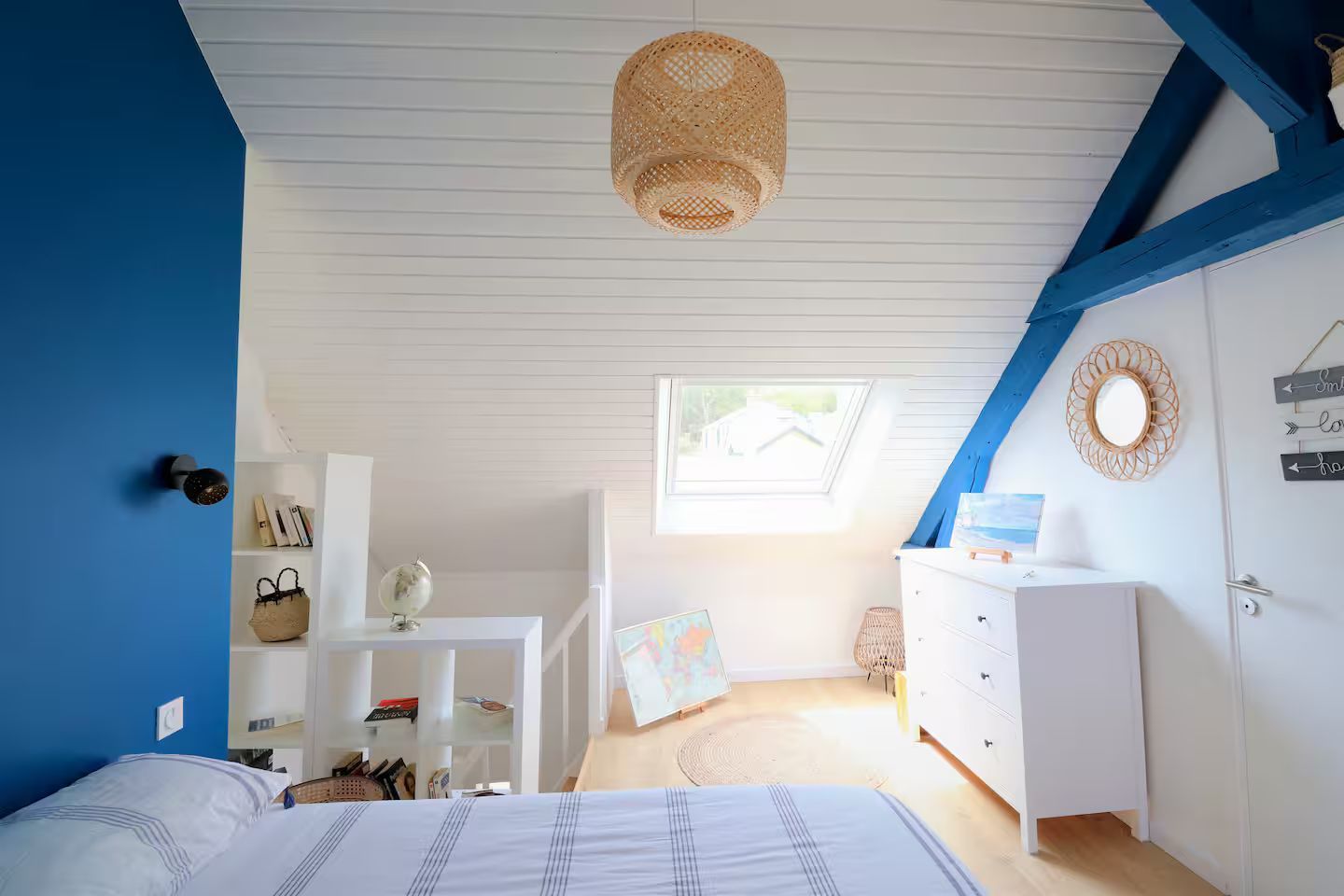 Une chambre avec un lit, une commode et des murs bleus.